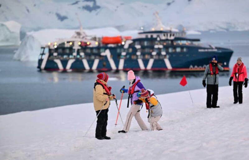 Multigenerational family group in Antarctica, having disembarked and walking on snow covered land