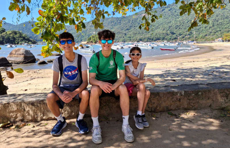 Kids in Brazil at Ilha Grande, sitting in the shade with sunny beach in the background