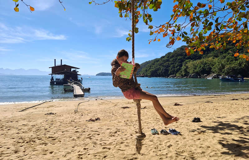 Child on beach reading on Brazil with kids holiday