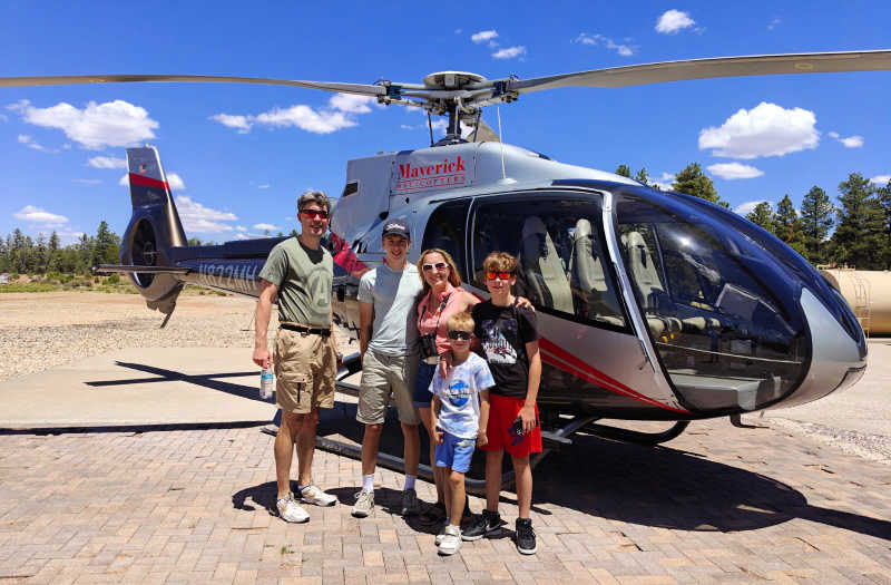 Family posing by a helicopter, on a tailor-made- family adventure in the USA arranged by Stubborn Mule Travel, about to fly over the Grand Canyon,