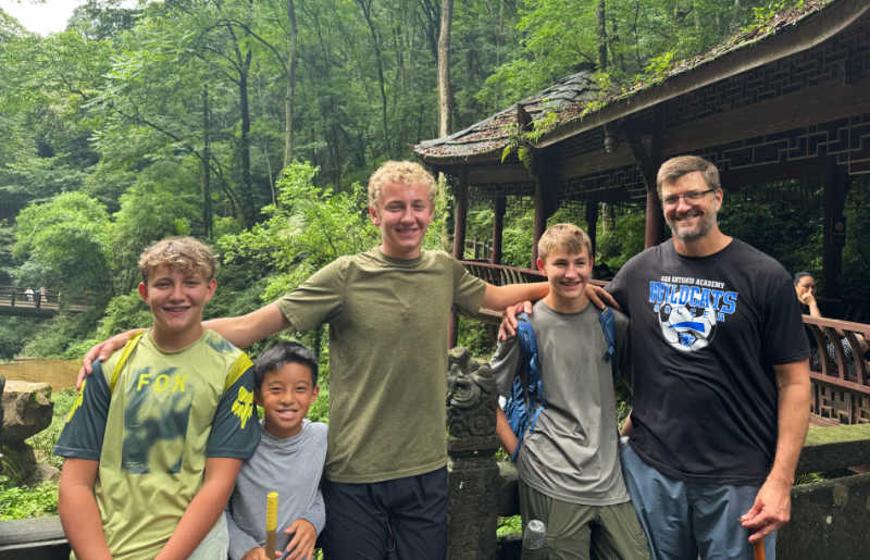 Family with four boys exploring verdant gardens in rural China on a holiday with kids