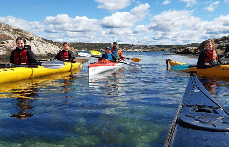 Family kayaking in Sweden on summer holiday, with guides