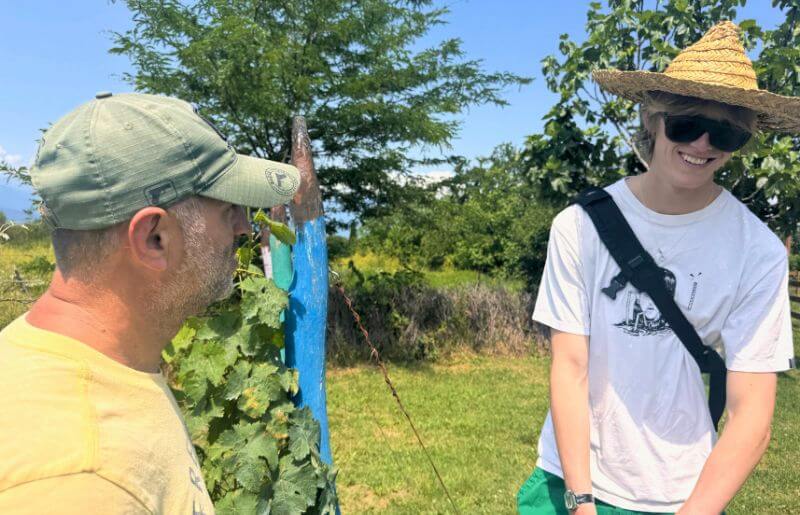 A man talks to a smiling teen about the vineyard they are standing in - Georgia holidays