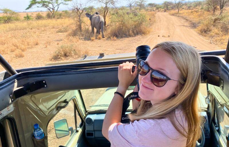Tanzania safari - young teenager on safari with camera and elephant in distance