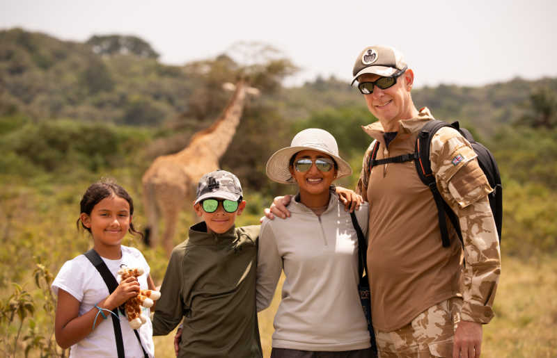Family walking with giraffe in Arusha, Tanzania on safari