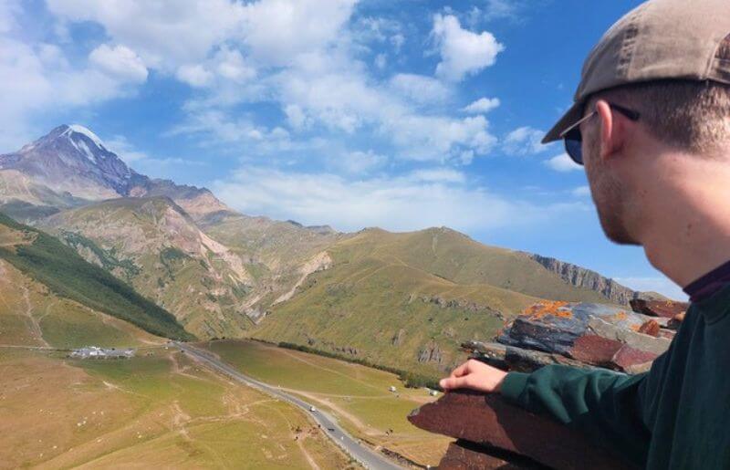 Older teenage boy looks out over the mountains of Georgia under blue skies