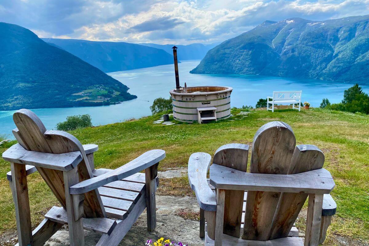 Two wooden seats overlooking a hot tub on the top of a mountain in Norway