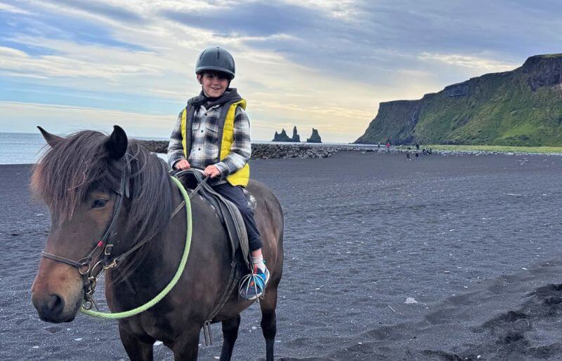 A young boy on horseback on an Icelandic beach