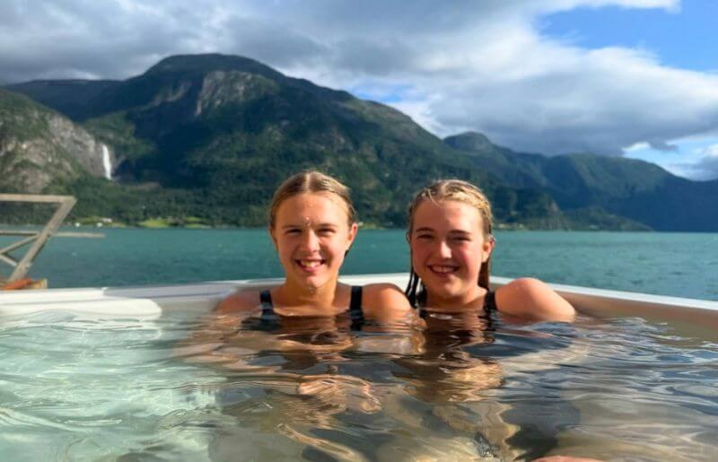 Teenagers enjoy a relaxing hot tub surrounded my the Norweigan ffjords.