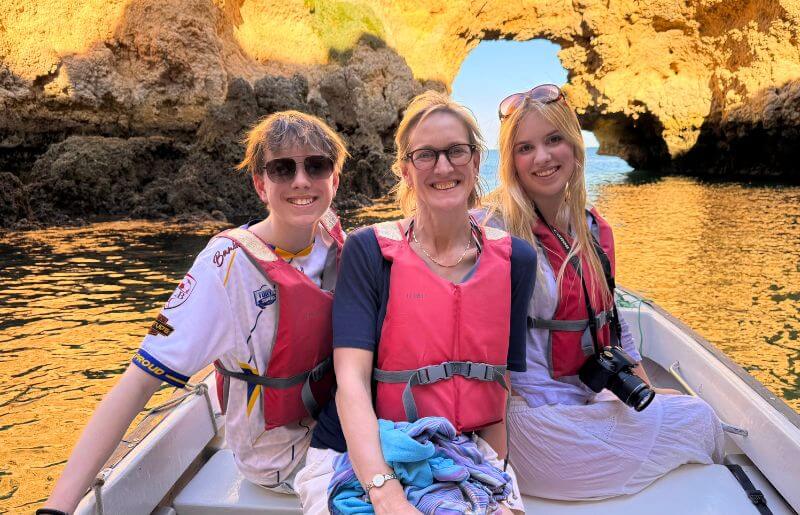 Mum and teenagers on a boat against rocks in Portugal